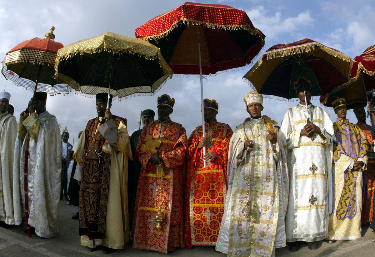 Ethiopian orthodox priests in their satin robes stand under sequined velvet umbrellas during the annual Epiphany celebrations called "Timket" of the Ethiopian Orthodox Church in Addis Ababa, January 20, 2004. "Timket", the greatest Ethiopian festival of the year is to commemorate Jesus Christ's baptism in the Jordan River by John the Baptist. 
