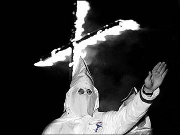 A white terrorist doing the Ku Klux Klan salute.