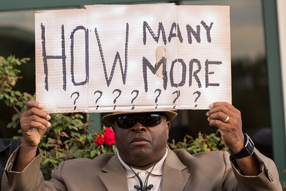 A man protests yet another act of white domestic terrorism and the death of innocent Black people.