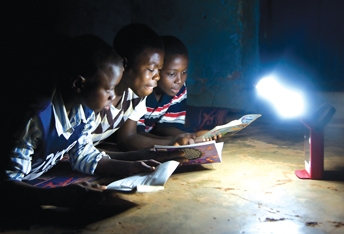 School boys gather to read by a light source while the electricity is down.
