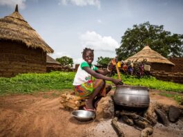 A young girl learns how to cook in the family compound in Burkina Faso, West Africa.