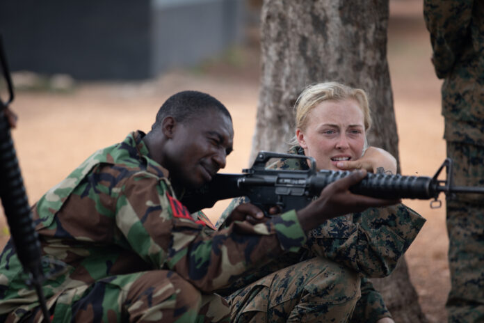 European woman teaching an African man how to shoot and kill other Africans... A mercenary under training. You've been invaded!
