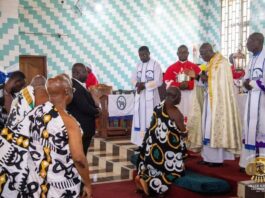 The King of the Asantes of Ghana kneeling in Christian Chruch before a priest.